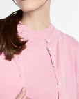 Close-up of a pink cardigan with button details on a white background