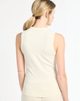 Woman wearing a beige sleeveless top and pants on a white background