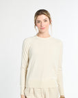 Woman wearing a beige sweater and pants on a white background