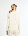 Woman wearing a beige long-sleeve top and pants on a white background