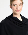 Woman wearing a black cowl-neck sweater against a white background