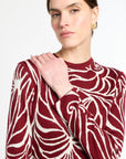 Woman wearing a red and white patterned sweater against a white background
