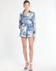 Woman wearing a blue and white floral blouse and shorts on a white background