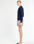 Woman wearing a navy sweater and patterned shorts on a white background