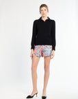 Woman wearing a black sweater and colorful floral shorts on a white background