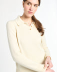 Woman wearing a cream-colored sweater against a white background
