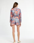 Woman wearing a colorful floral romper on a white background