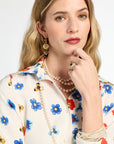Woman wearing a floral blouse with a pearl necklace and earrings against a white background