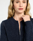 Woman wearing a navy blue jacket with a zipper on a plain background