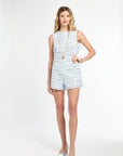 Woman wearing a light blue plaid romper on a white background