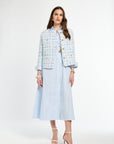 Woman wearing a light blue tweed jacket and matching skirt on a white background
