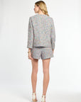Woman wearing a patterned blazer and shorts set on a white background