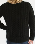 Back view of Eleanor Leftwich wearing the cable knit Fisherman Crewneck in Black, paired with dark jeans, standing against a white background.