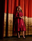 Woman in a red dress standing on a stage with red curtains