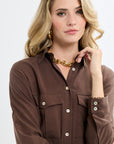 Woman wearing a brown shirt with a gold necklace on a white background