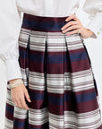 Person wearing a white shirt and a plaid skirt with red and blue stripes on a white background