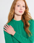 Woman wearing a cashmere silk knit green sweater against a white background