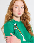 Woman wearing a green sweater with a giraffe design on a white background
