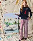 Woman modeling a navy sweater with a giraffe on a paint splatter background