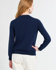 Woman wearing a navy blue sweater and white pants on a white background
