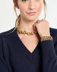 close up of woman wearing navy v-neck sweater with gold jewelry