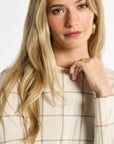 Close-up of the cream windowpane plaid neckline and knit texture of the Reversible Crewneck, photographed against a plain white studio background.