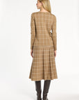 A woman modeling the chestnut side of the Windowpane Plaid Reversible Crewneck with the matching skirt, back view, photographed against a plain white studio background.