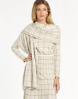 A woman modeling the cream side of the Chestnut Windowpane Plaid Reversible Wrap draped over the matching skirt and crewneck, front view, photographed against a plain white studio background.