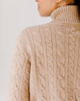 Close up of model wearing the Camel Cable-Knit Turtleneck sweater showcasing the sweater's quality design and comfortable texture.