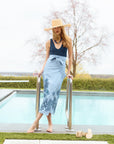 Woman wearing a navy swimsuit and blue embroidered floral skirt outside