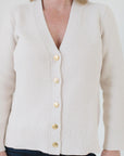 Close-up of Eleanor Leftwich wearing The Perfect Cardigan in cream, paired with jeans, and highlighting the handcrafted Italian gold buttons.