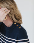 Close-up of EL wearing the Perfect Striped Crewneck in navy with cream mariner stripes, highlighting the handcrafted Italian gold buttons.