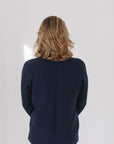 Back view of Eleanor Leftwich wearing The Perfect Cardigan in navy, paired with white jeans, and facing a white background.
