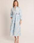 Woman wearing a light blue floral dress with a belt on a white background
