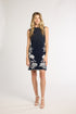 Woman modeling a black dress with white fern detailing on a white backdrop