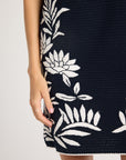 Close up of black hand-crochet dress with white floral detailing on the side
