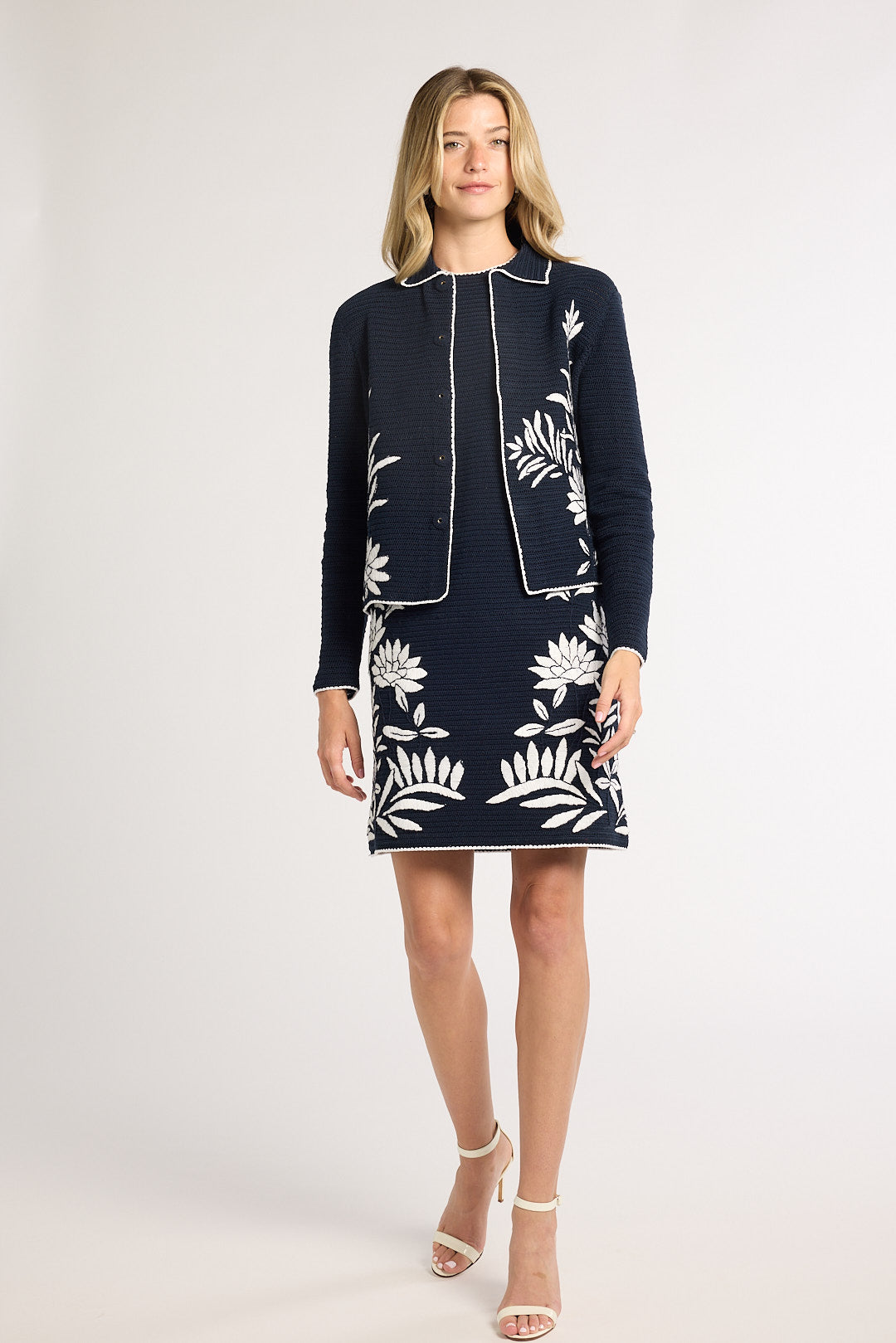 Woman modeling a black jacket with fern detailing on the front in a studio