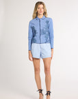 Woman modeling a light blue jacket with fern detailing on the sides on a white backdrop