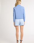 Woman modeling a blue jacket and blue shorts on a white background