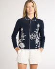 Woman modeling a black jacket with white fern detailing