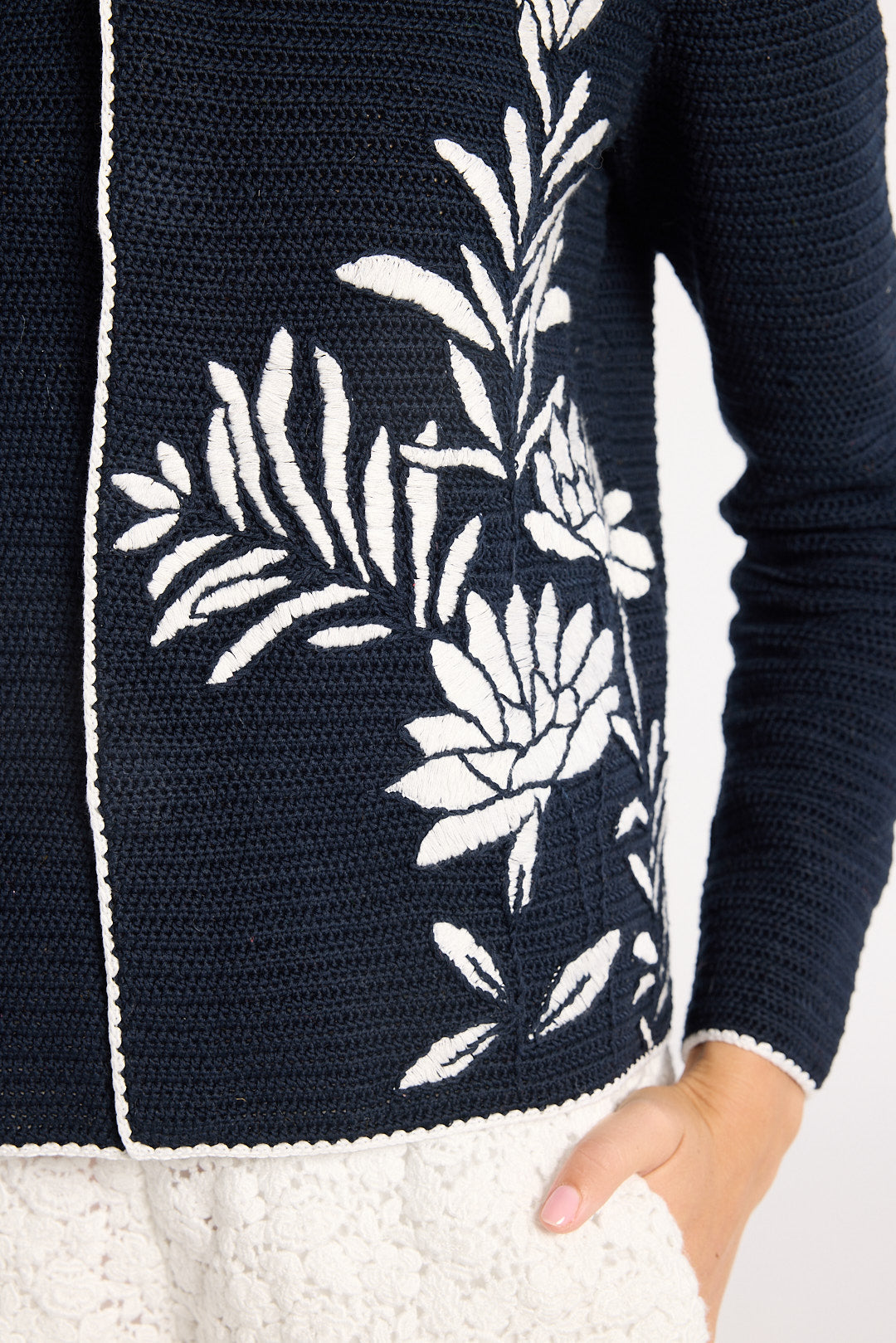 Close up of white detailing on a black hand-crochet jacket on a white backdrop