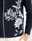 Close up of white detailing on a black hand-crochet jacket on a white backdrop