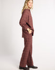 A woman modeling a matching two-piece plaid lounge set in a dusty rose-brown color, featuring a long-sleeve button-up shirt and wide-leg trousers, paired with black leather shoes against a plain white studio background.