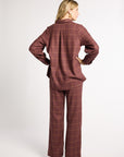 A woman is shown from the back wearing a matching two-piece plaid lounge set in a dusty rose-brown color. The set includes a long-sleeve button-up shirt and wide-leg trousers, photographed against a plain light gray studio background.
