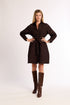 Woman wearing a brown brocade dress with a matching belt and brown boots on a white background