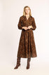 Woman wearing a brown patterned dress and boots on a white background