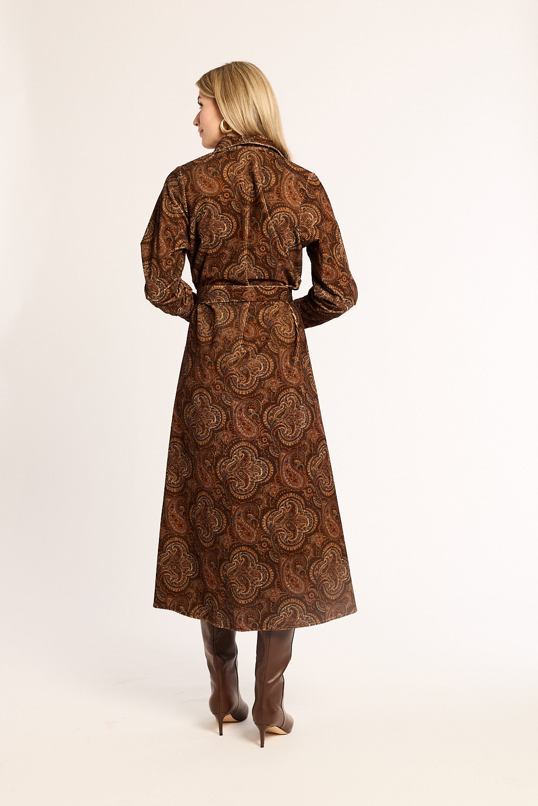 Woman wearing a brown paisley patterned coat on a white background