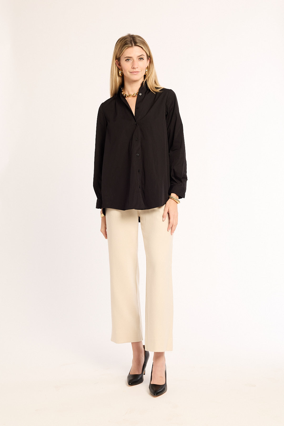 Woman wearing a black shirt and beige pants on a white background