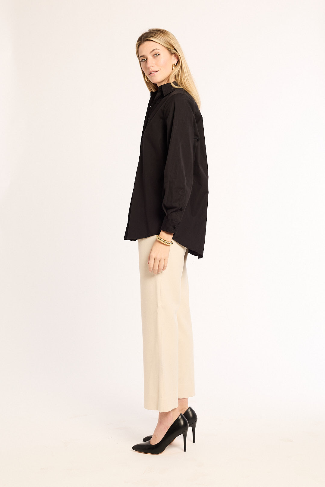 Woman wearing a black shirt and beige pants on a white background