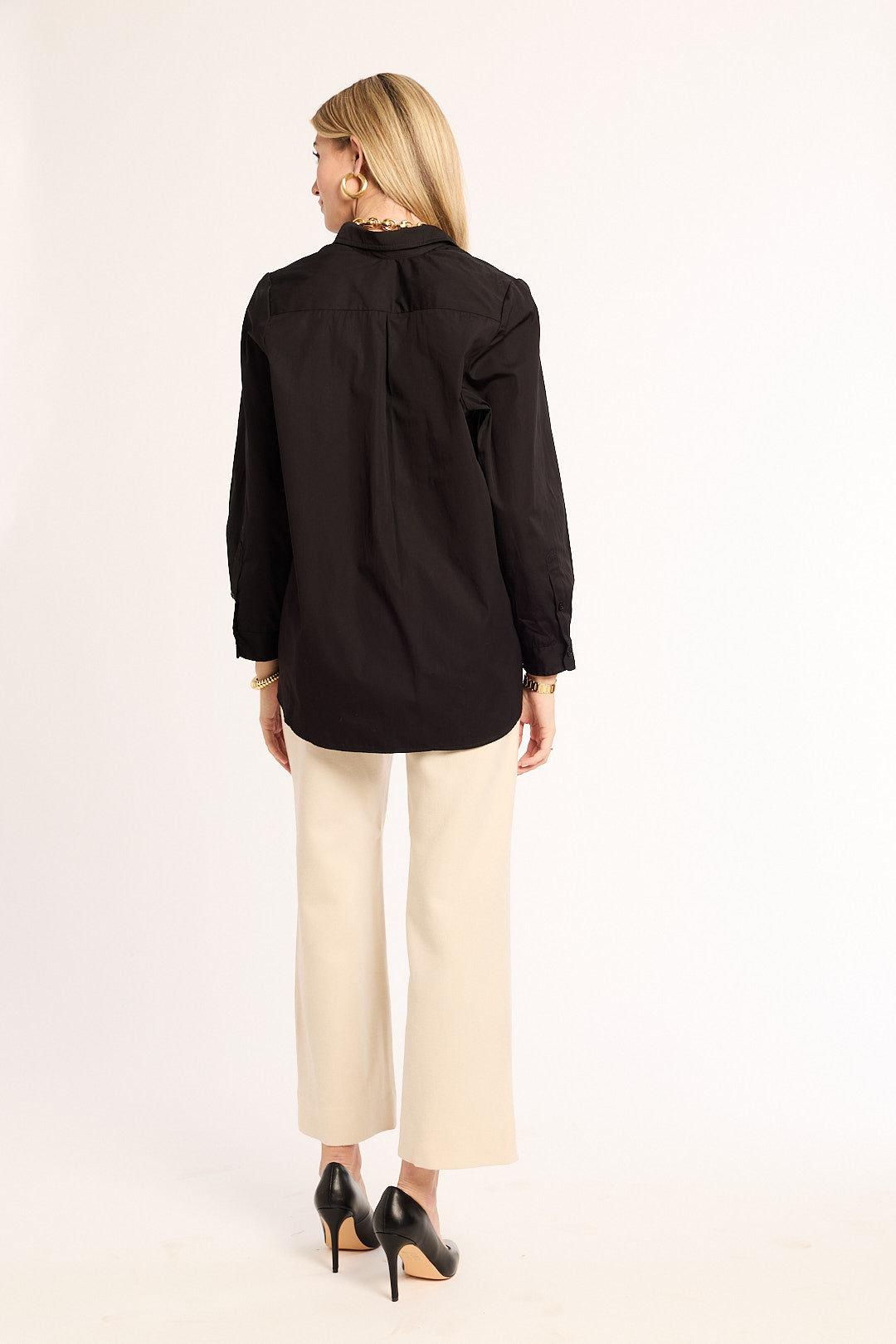 Woman wearing a black shirt and beige pants on a white background